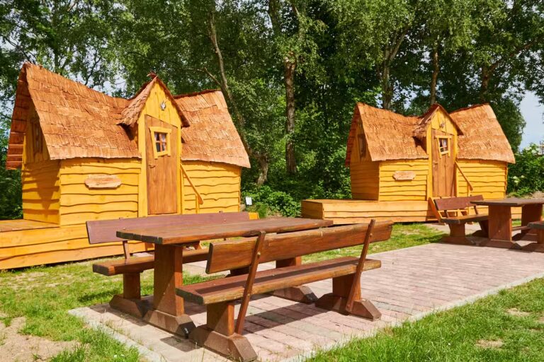Ostseecamping Familie Heide ausgefallene hoelzerne Klabauterhuetten Mietunterkuenfte mit kleiner Terrasse und gemuetlichen Baenken und Tischen auf einer gepflasterten Gemeinschaftsterrasse 10d9d050 b615 4754 9144 31e241231f91 768x512