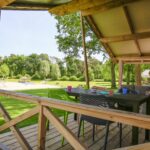 Camping De Paal Die Veranda eines Bungalows mit Sitzgelegenheiten darauf 150x150
