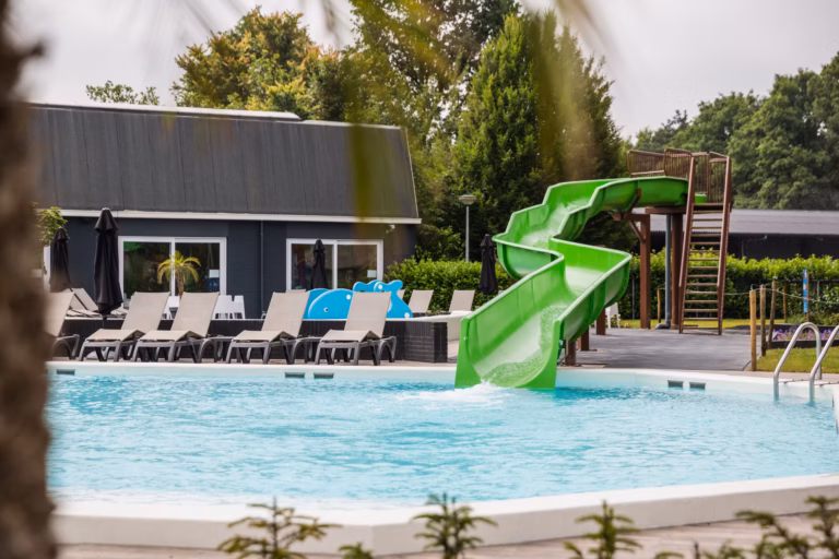 Familiecamping De Belten Pool mit Rutsche Liegestuehlen und Sonnenschirmen auf dem Campingplatz 768x512