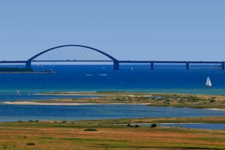 Camping Fluegger Strand Strand in der Naehe des Campingplatzes mit Bruecke in der Ferne 768x512