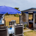 Camping Fluegger Strand Wohnwagen mit Esstisch und Regenschirm  150x150