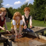 Camping Suedstrand Kinder beim Wasserspiel im Gruenen auf dem Campingplatz 150x150