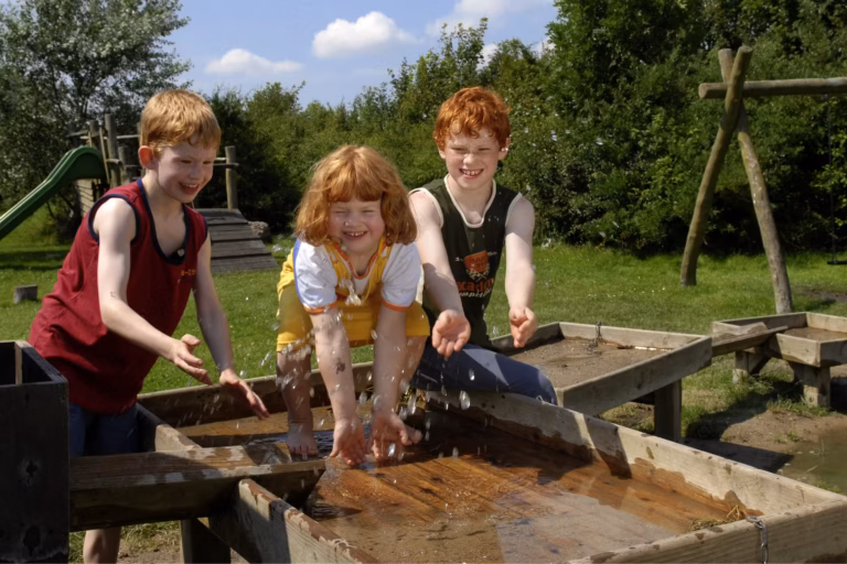 Camping Suedstrand Kinder beim Wasserspiel im Gruenen auf dem Campingplatz 768x512