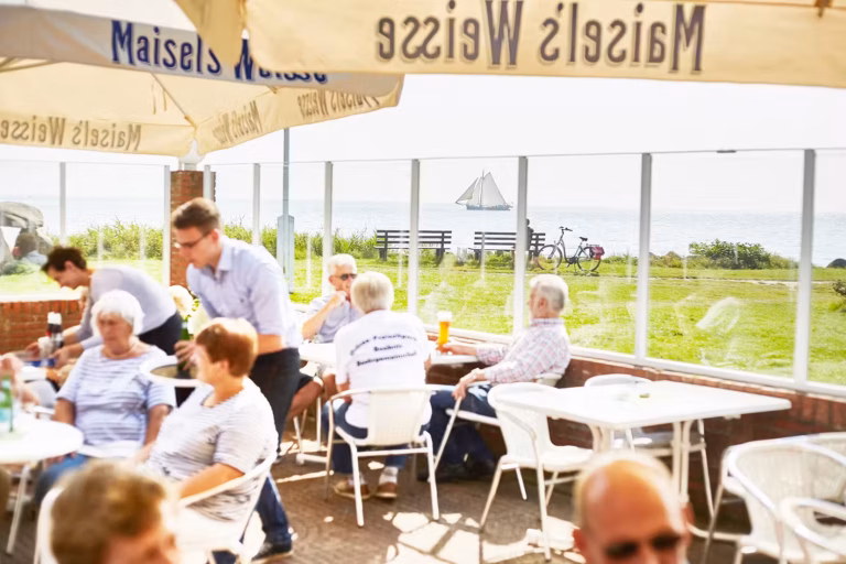 Ostsee Freizeitpark Booknis Veranda von dem Restaurant mit Sonnenschirmen mit Blick auf das Meer auf dem Campingplatz 768x512